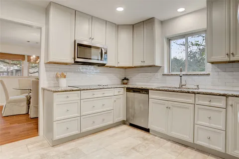 a kitchen with granite countertop white cabinets sink and stainless steel appliances