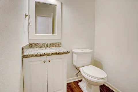 a bathroom with a granite countertop toilet sink and mirror