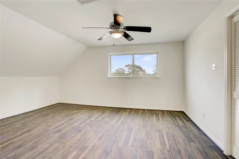 an empty room with wooden floor ceiling fan and window
