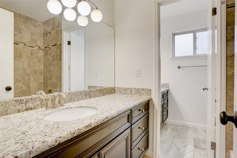 a bathroom with a granite countertop sink a mirror and a shower