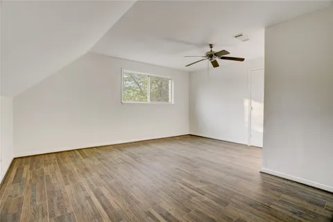an empty room with wooden floor chandelier fan and windows