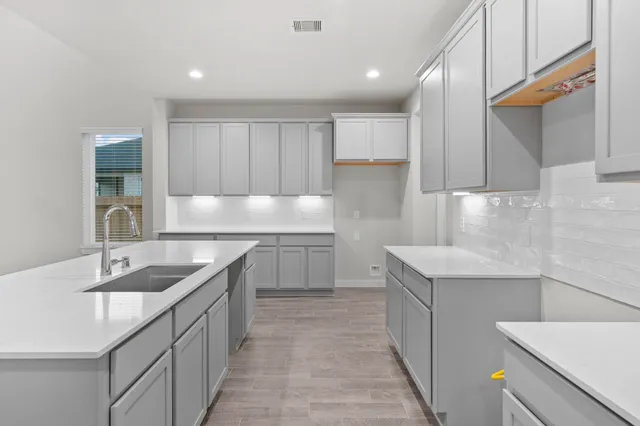 a kitchen with kitchen island granite countertop a sink and white cabinets