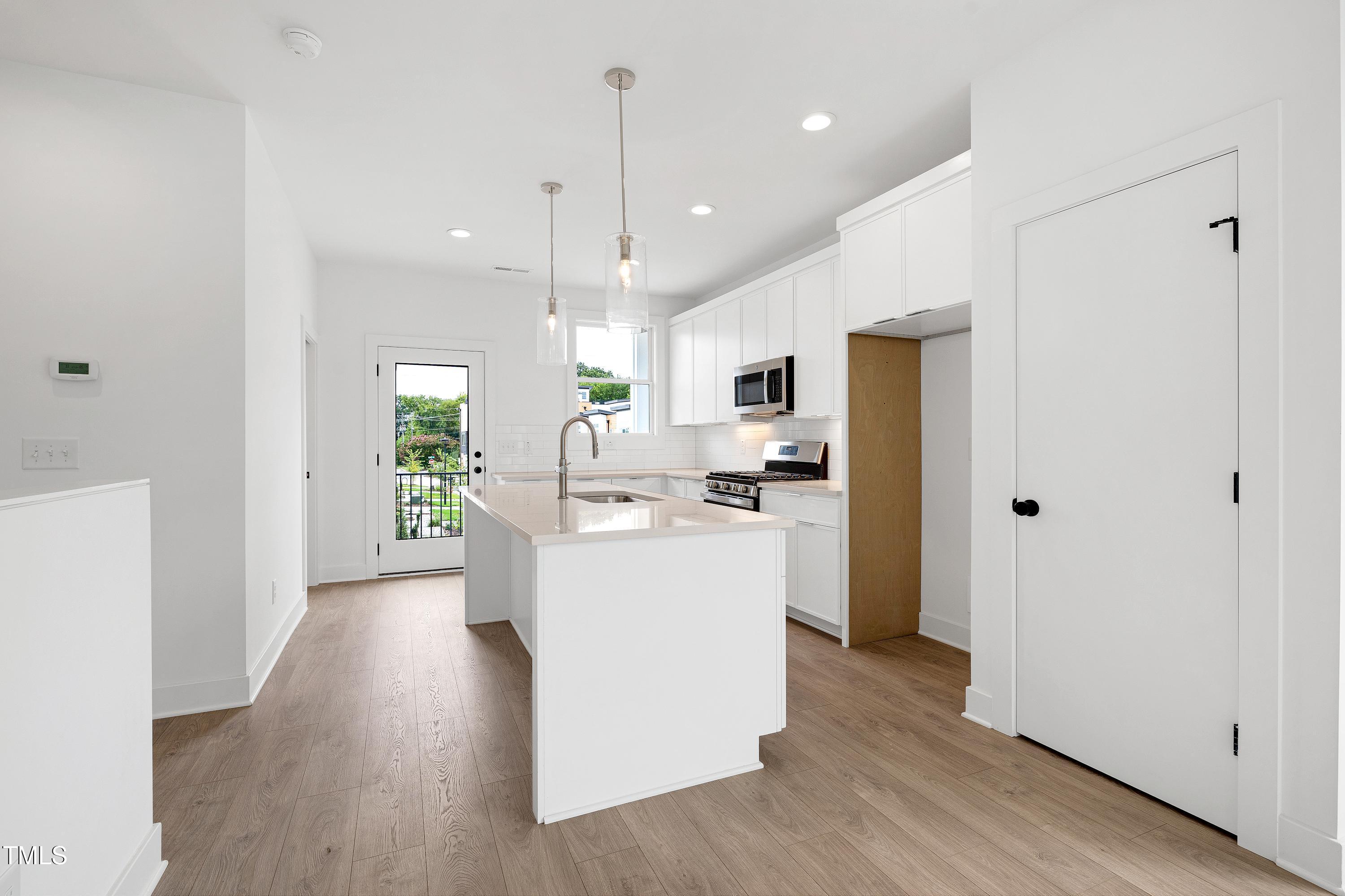 1412 Sawyer Road, Unit 101 Raleigh, NC 27610 - Photo 11 of 33 a kitchen with kitchen island white cabinets and stainless steel appliances