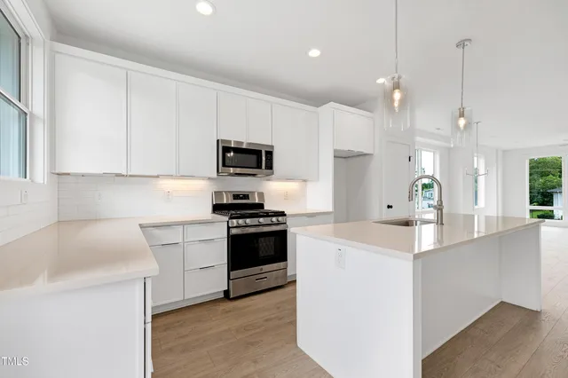a kitchen with kitchen island white cabinets and stainless steel appliances