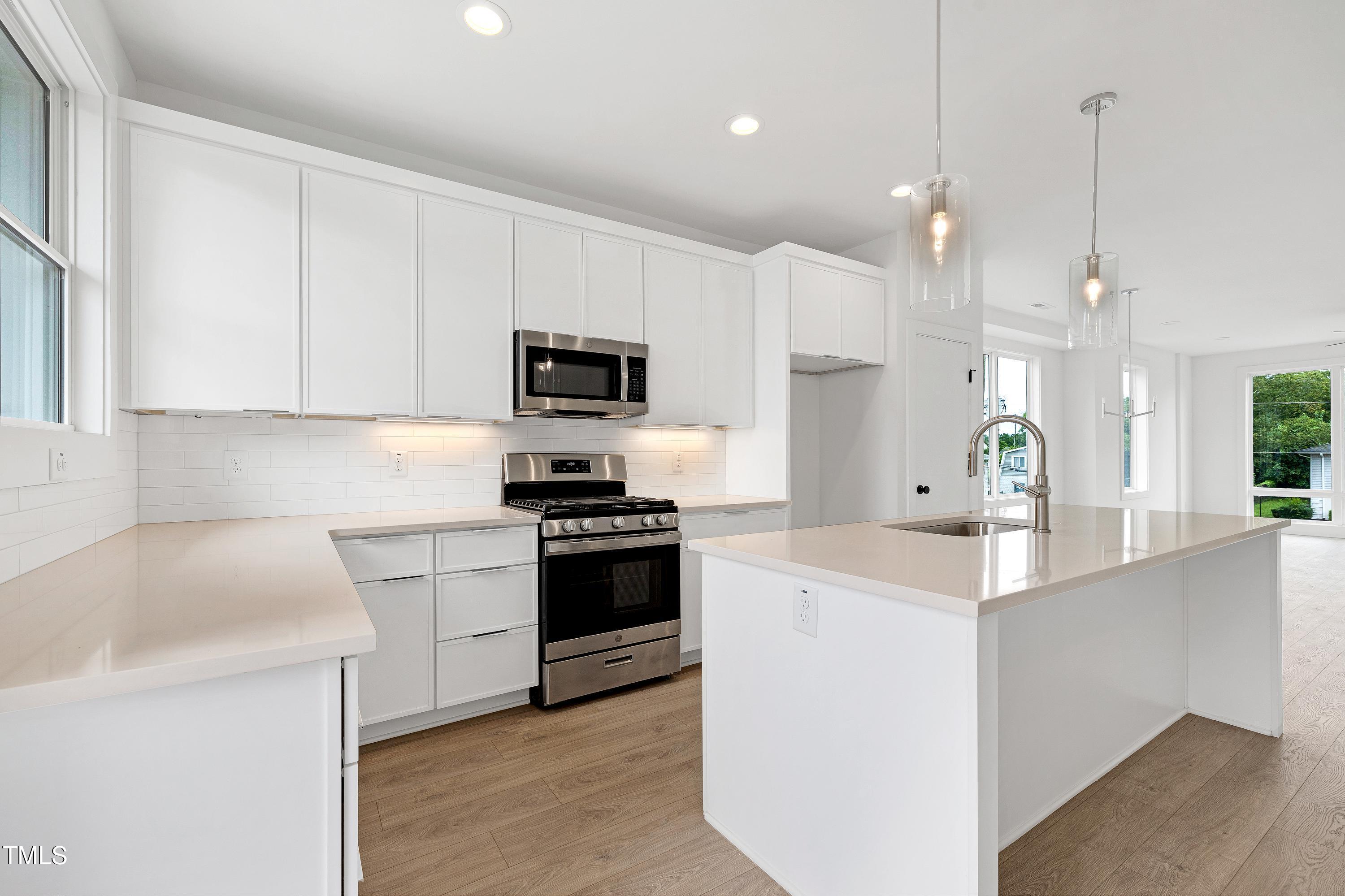 1412 Sawyer Road, Unit 101 Raleigh, NC 27610 - Photo 12 of 33 a kitchen with kitchen island white cabinets and stainless steel appliances