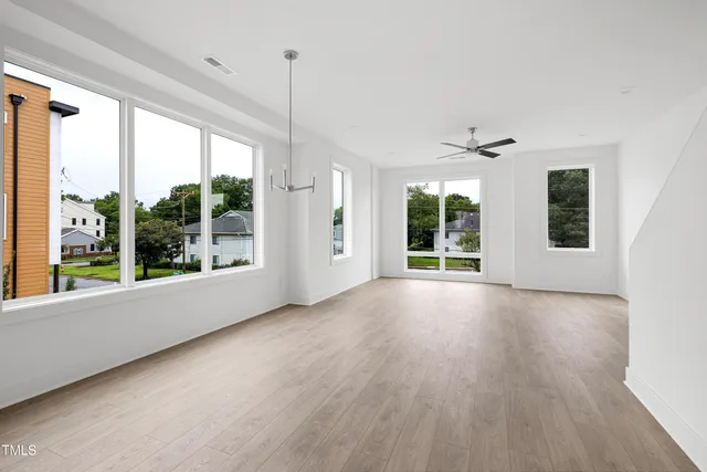 a view of an empty room with a window and wooden floor