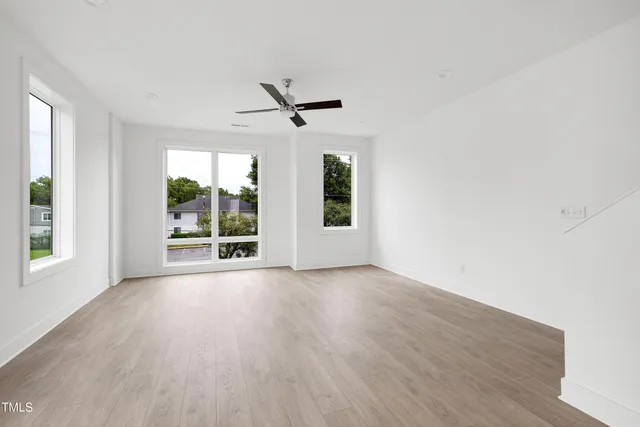 an empty room with wooden floor and windows