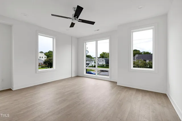 a view of an empty room with wooden floor and a window