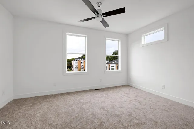 an empty room with windows and ceiling fan