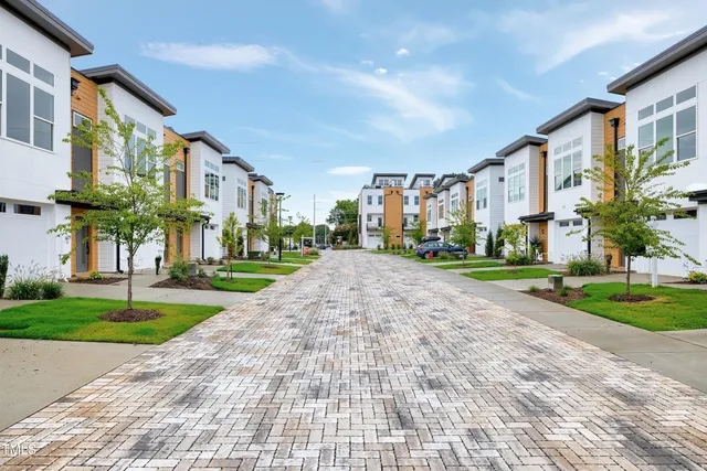 a front view of a residential apartment building with a yard and potted plants