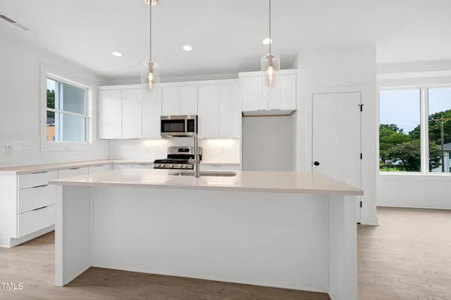 a kitchen with kitchen island white cabinets and refrigerator