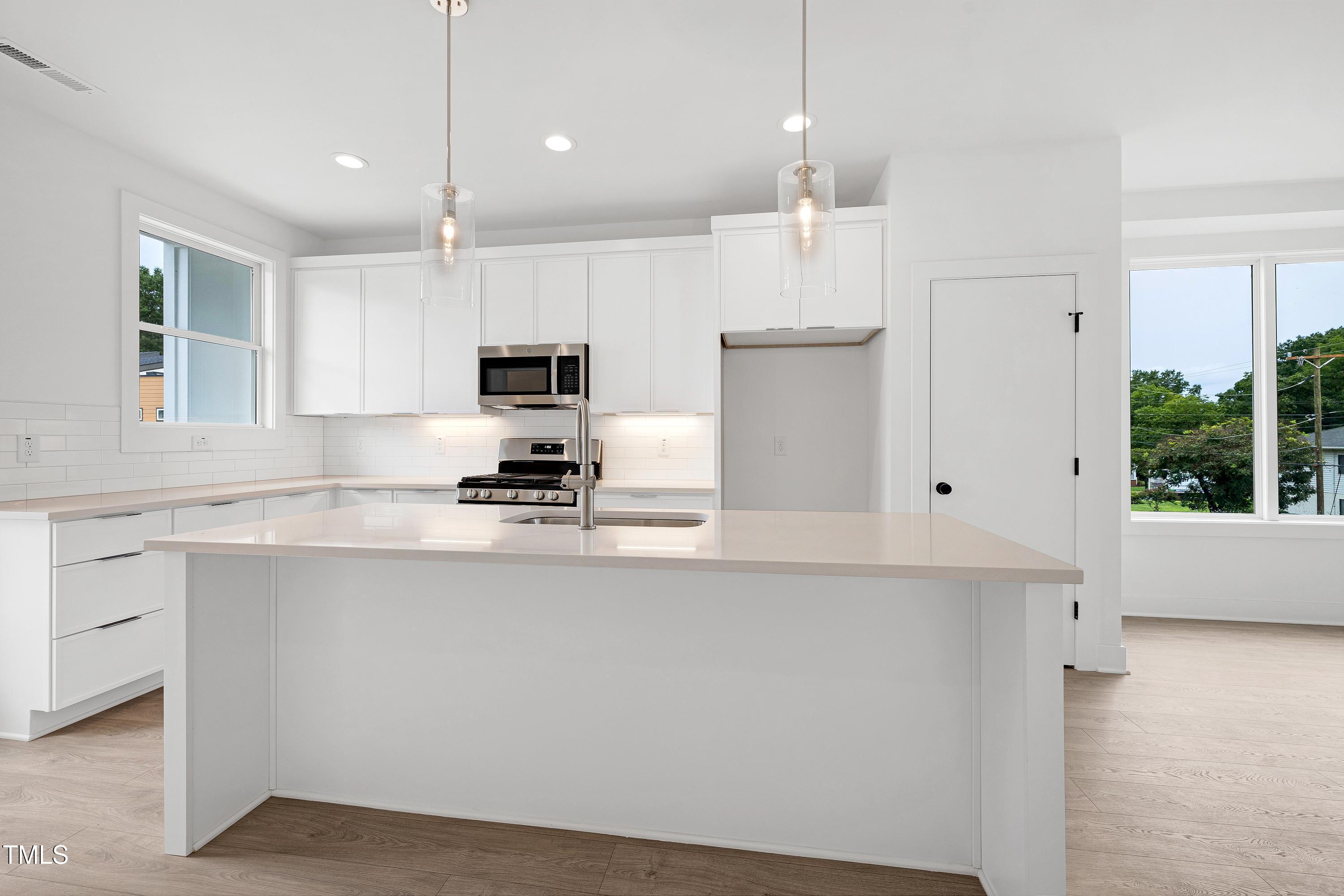 1412 Sawyer Road, Unit 101 Raleigh, NC 27610 - Photo 10 of 33 a kitchen with kitchen island white cabinets and refrigerator