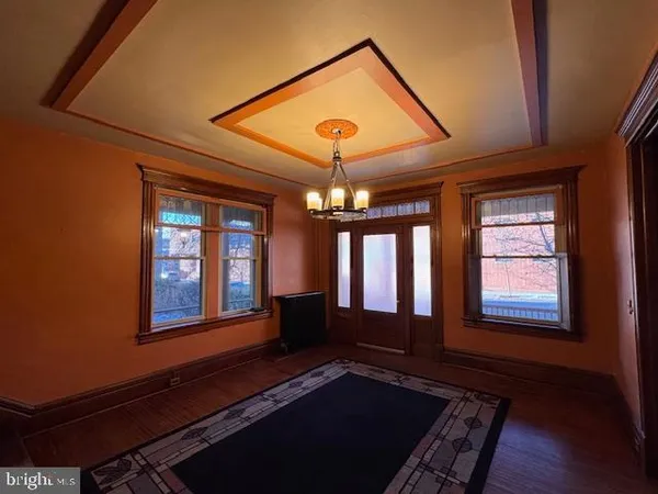 an empty room with wooden floor fireplace and windows