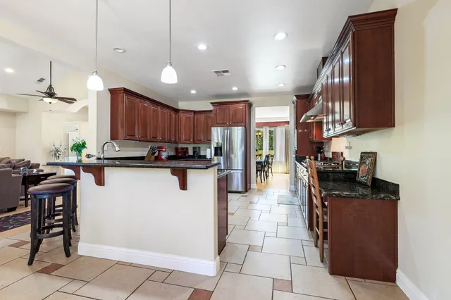 a kitchen with stainless steel appliances granite countertop a refrigerator a sink a stove a microwave and wooden cabinets