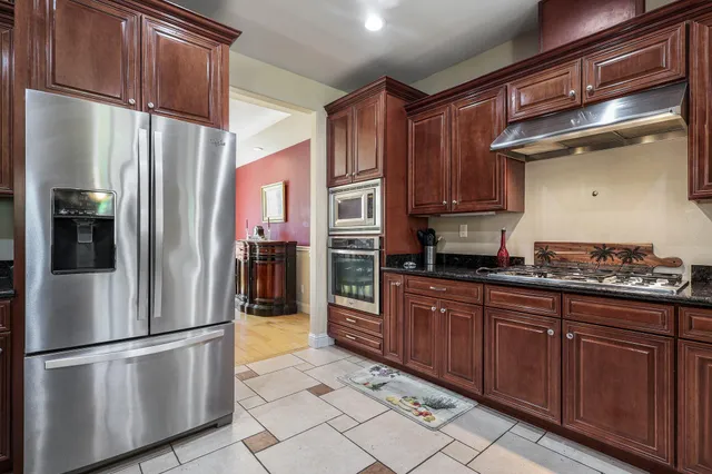 a kitchen with stainless steel appliances granite countertop a refrigerator a sink and wooden cabinets