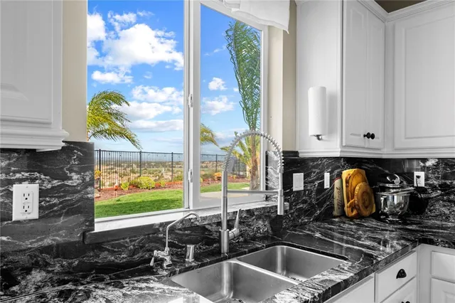 a kitchen with granite countertop a stove a sink a dining table and chairs with wooden floor