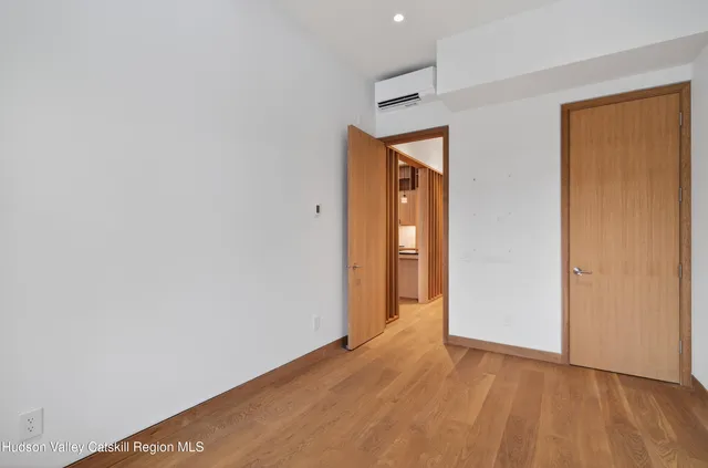 a view of an empty room with wooden floor and closet