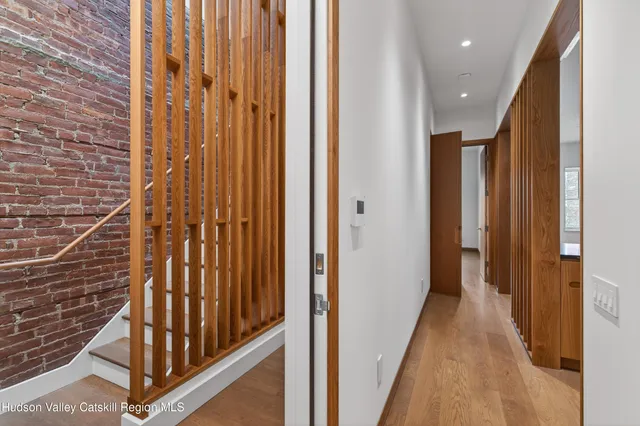 a view of a hallway with wooden floor and staircase