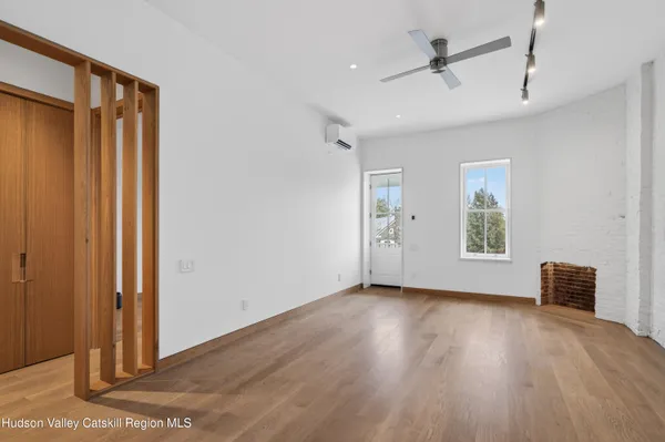 a view of an empty room with wooden floor and a window