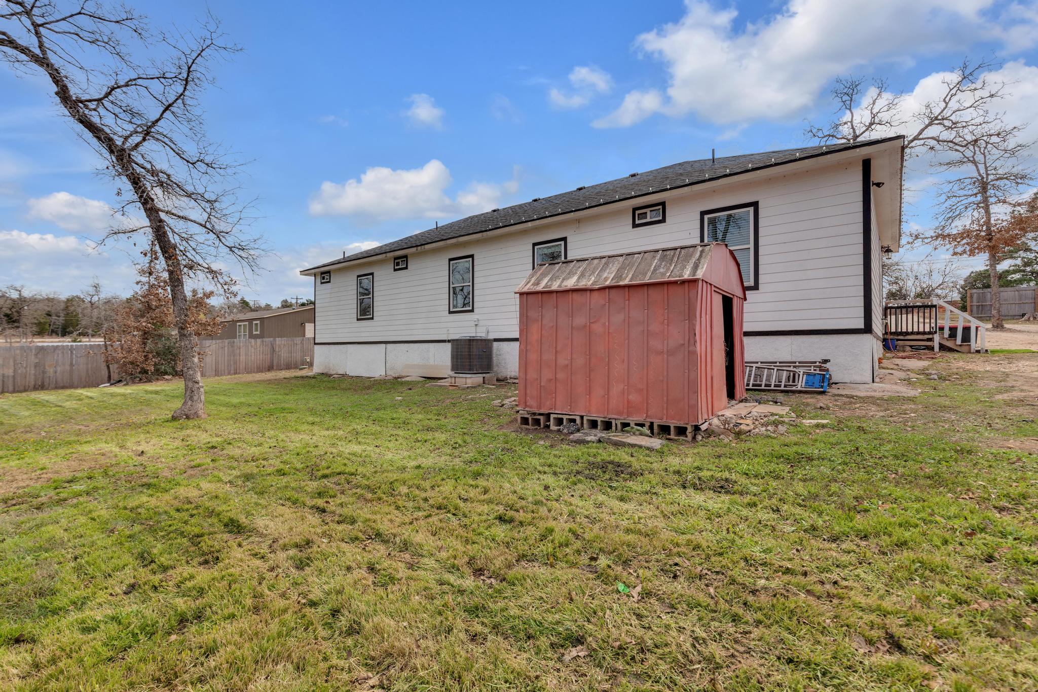 114 Crepe Myrtle Parkway Elgin, TX 78621 - Photo 30 of 40 Rear view of property featuring a storage unit and a wooden deck