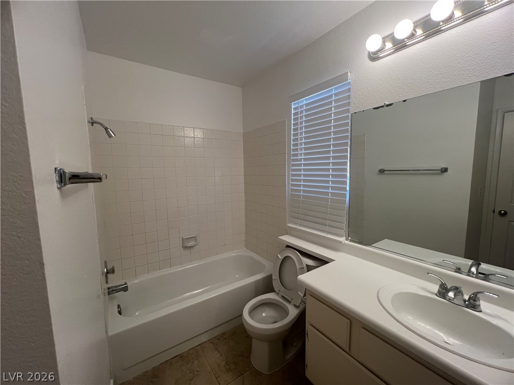 1309 Goldenglow Road Las Vegas, NV 89108 - Photo 10 of 11 A well-lit washroom features a combined shower and tub, complemented by a broad vanity and tile flooring.