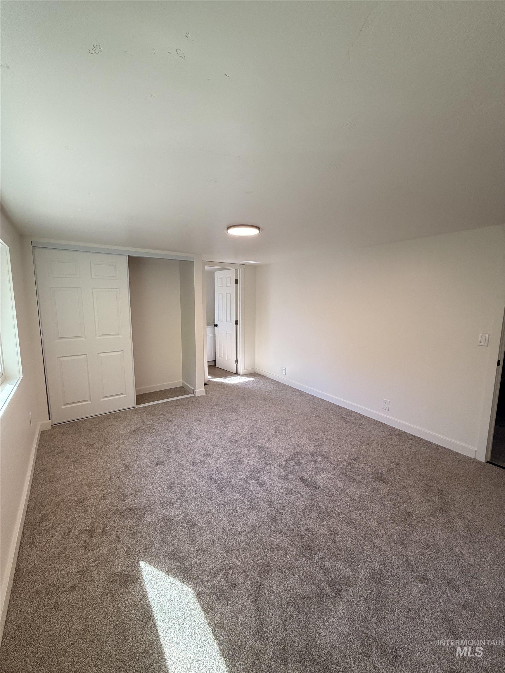 151 View Road Kamiah, ID 83536 - Photo 20 of 49 Spacious room featuring new gray carpet flooring, white painted walls, a flush-mount ceiling light fixture, bi-fold closet doors, and white baseboards