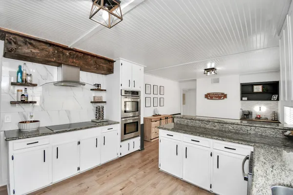 a kitchen with a sink dishwasher a stove and white cabinets with wooden floor