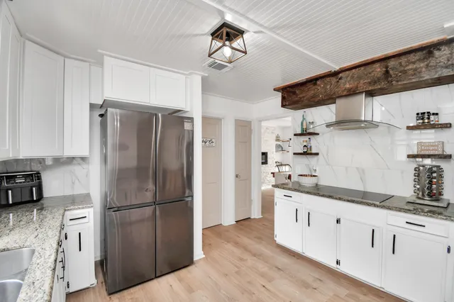 a kitchen with stainless steel appliances granite countertop a refrigerator a stove and a sink with wooden floor