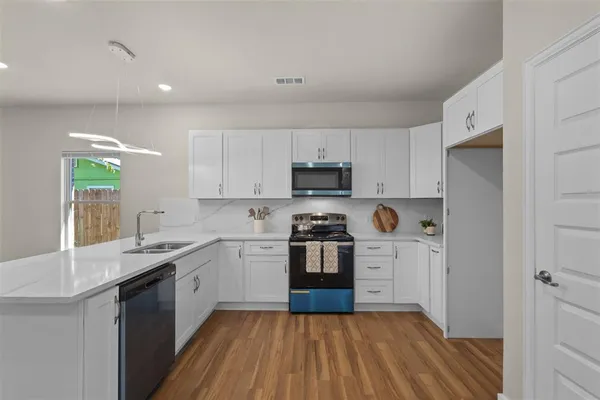 a kitchen with stainless steel appliances a sink a stove a refrigerator and cabinets