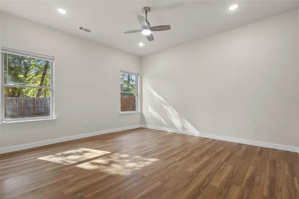 a view of an empty room with wooden floor and a window