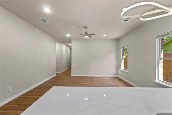 an empty room with wooden floor chandelier and windows