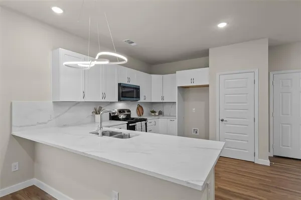 a kitchen with stainless steel appliances granite countertop a sink a stove and a refrigerator with wooden floor