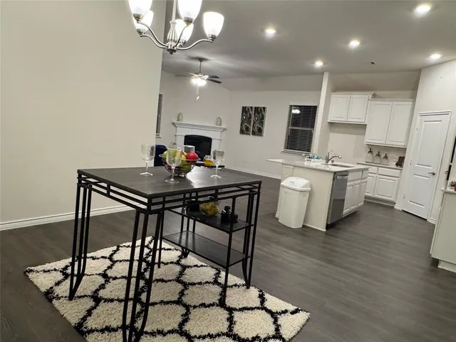 a kitchen with stainless steel appliances kitchen island a table chairs and a refrigerator
