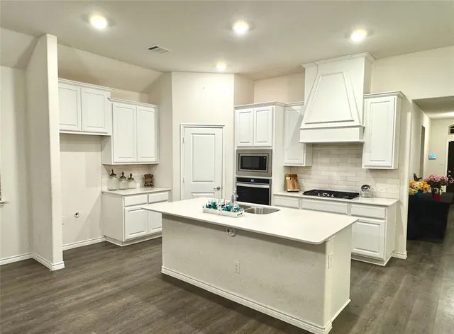 a kitchen with stainless steel appliances granite countertop a stove a sink a refrigerator and white cabinets