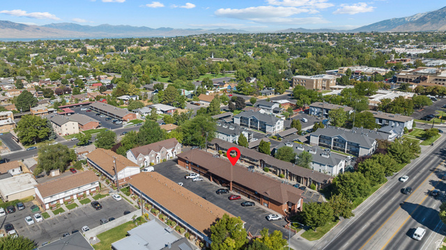 865 North 500 West, Unit 5 Provo, UT 84604 - Photo 14 of 14 Aerial perspective showcasing multiple residential structures with brown roofing, extensive paved parking areas, and mature green landscaping