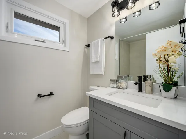 a bathroom with a granite countertop sink a toilet and mirror
