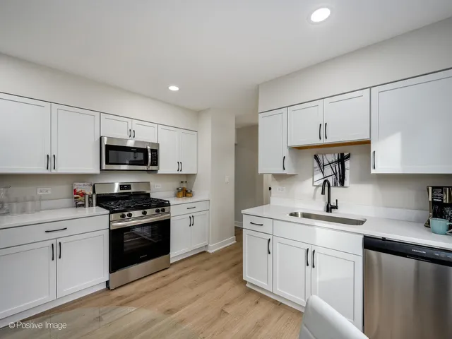 a kitchen with granite countertop white cabinets sink and stainless steel appliances