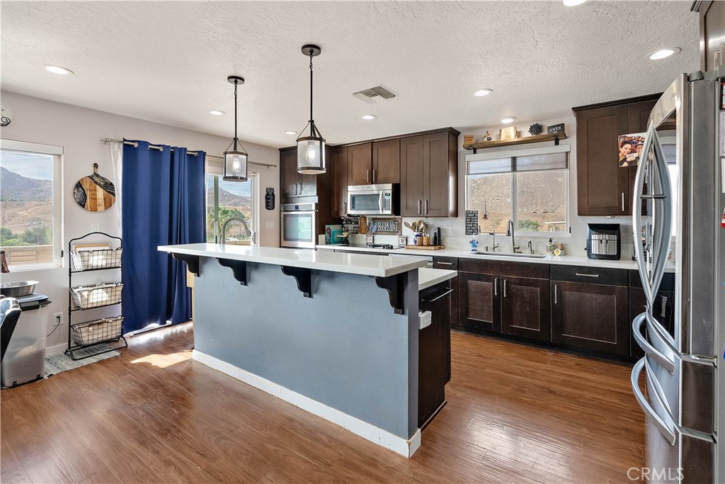 24444 Scotch Lane Colton, CA 92324 - Photo 14 of 43 a kitchen with stainless steel appliances granite countertop wooden floors wooden cabinets a sink and a fireplace
