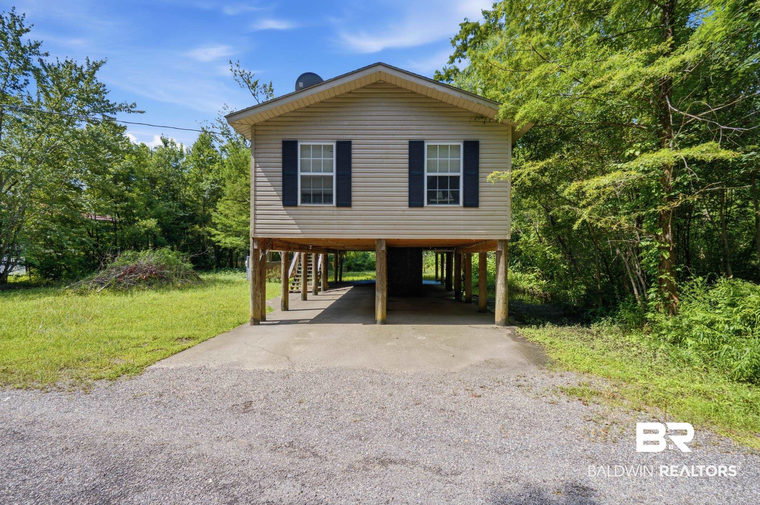 42080 Bayou Road Bay Minette, AL 36507 - Photo 2 of 43 Stilted residence featuring beige siding, black louvered shutters, and a covered parking area beneath
