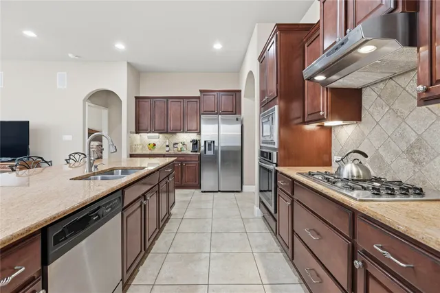 a kitchen with stainless steel appliances granite countertop a sink stove and refrigerator