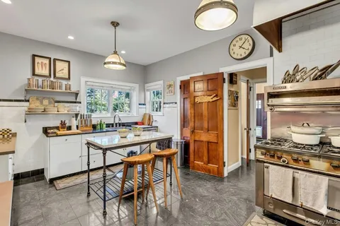a kitchen with stainless steel appliances granite countertop a stove a refrigerator a sink a dining table and chairs with wooden floor