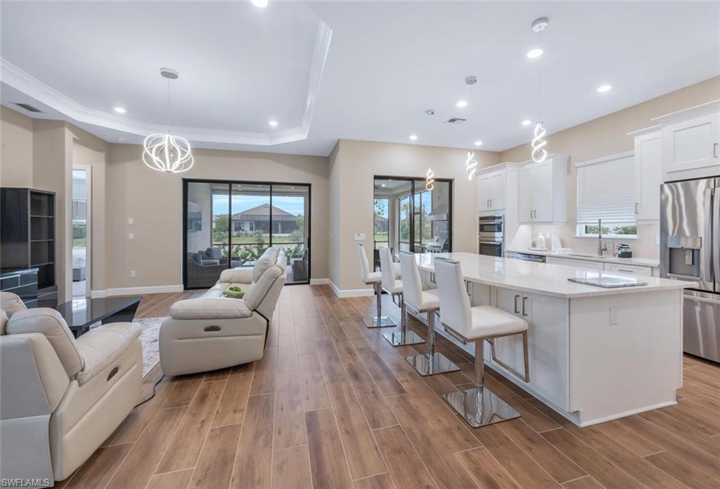 8448 Rosa Court Naples, FL 34114 - Photo 5 of 24 Open concept living area featuring wood-finish flooring and a tray ceiling with recessed lighting