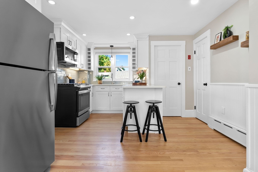 17 Coolidge Street Stoneham, MA 02180 - Photo 7 of 37 a kitchen with stainless steel appliances granite countertop a refrigerator a stove a sink dishwasher and a refrigerator with wooden floor