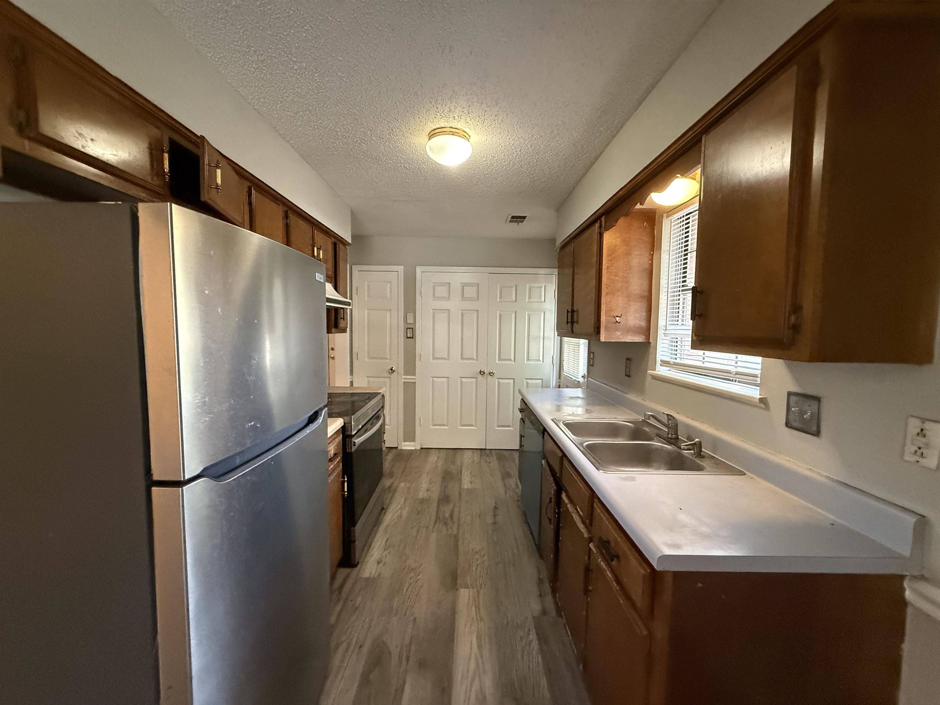 6420 Saginaw Road Memphis, TN 38134 - Photo 7 of 38 Galley kitchen featuring wood-finish cabinetry, light-toned countertops, and wood-finish flooring
