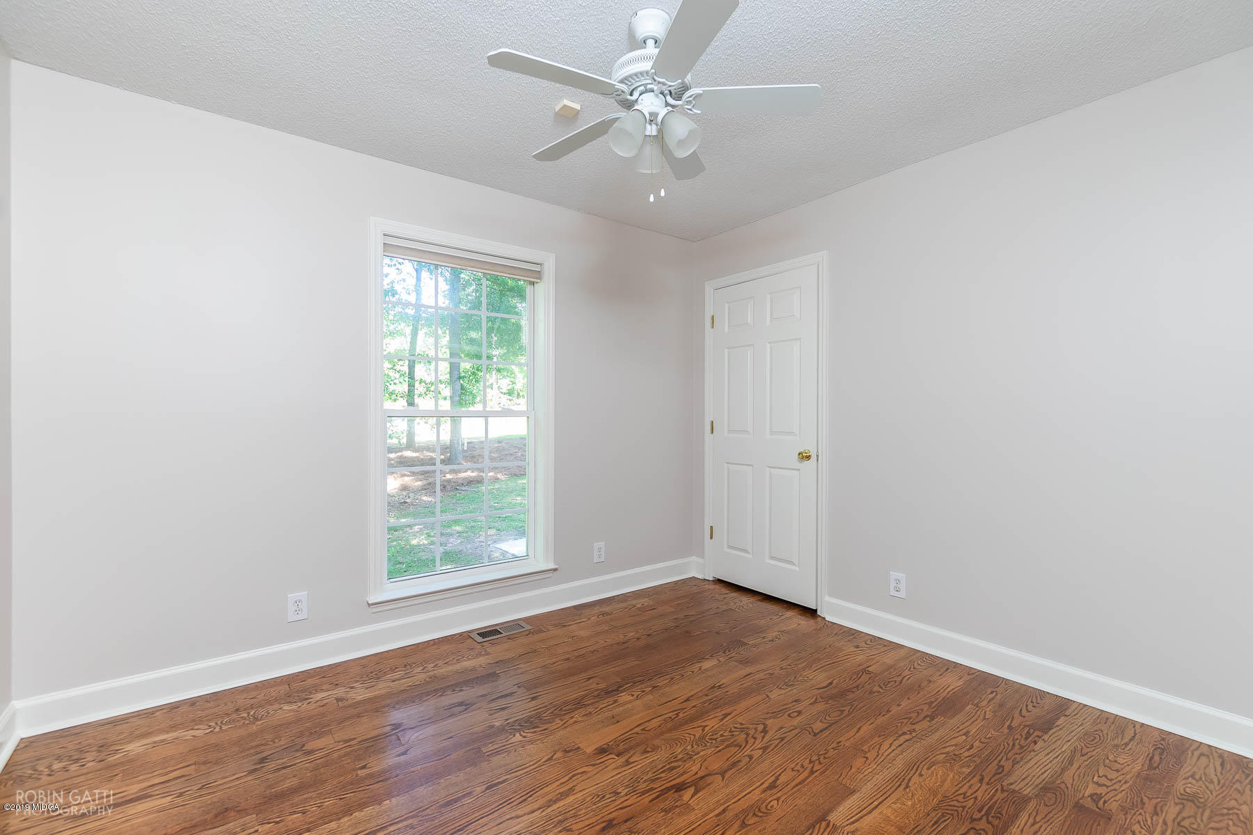 6840 Skipper Road Macon, GA 31216 - Photo 22 of 37 an empty room with wooden floor ceiling fan and windows