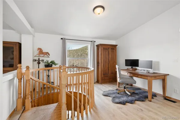 a view of a workspace with wooden floor and windows