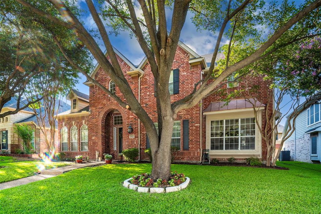 a front view of a house with a yard and large trees
