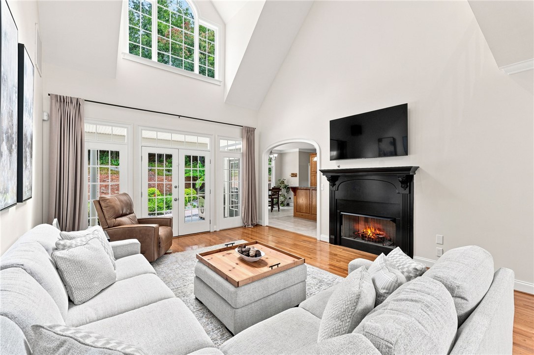 Soaring vaulted ceilings and a classic fireplace anchor this light-filled living space with hardwood floors.