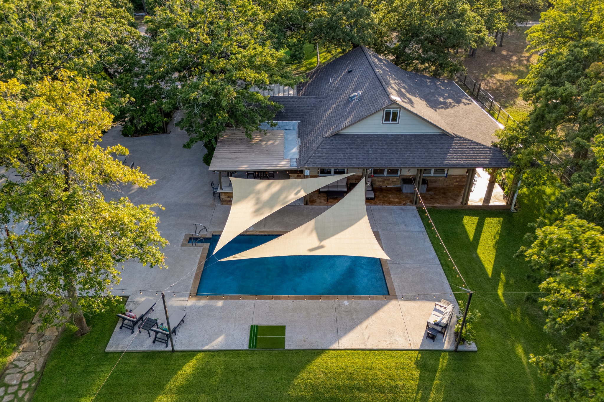 1474 County Rd B Lexington, TX 78947 - Photo 25 of 34 An inviting backyard oasis offers a sparkling pool with shade sails, perfect for leisure and outdoor enjoyment.