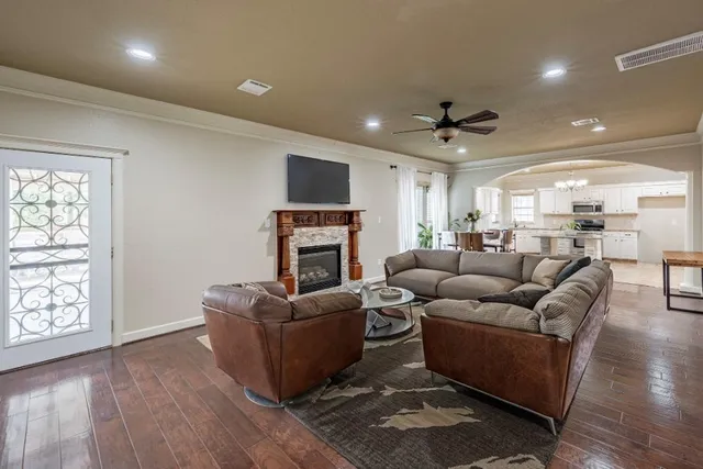 a living room with furniture a ceiling fan a flat screen tv and a fireplace